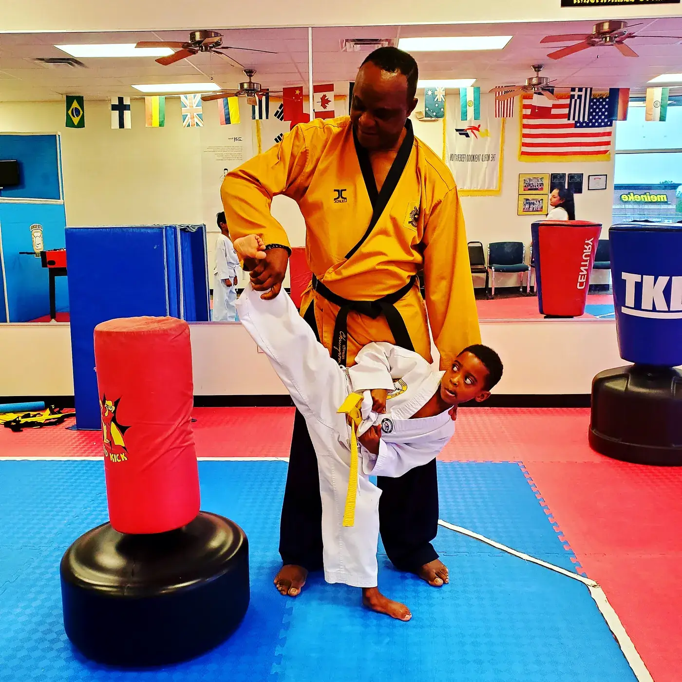 GrandMaster Pius coaching a young student through a high kick at Master Pius Martial Arts in Sandy Springs