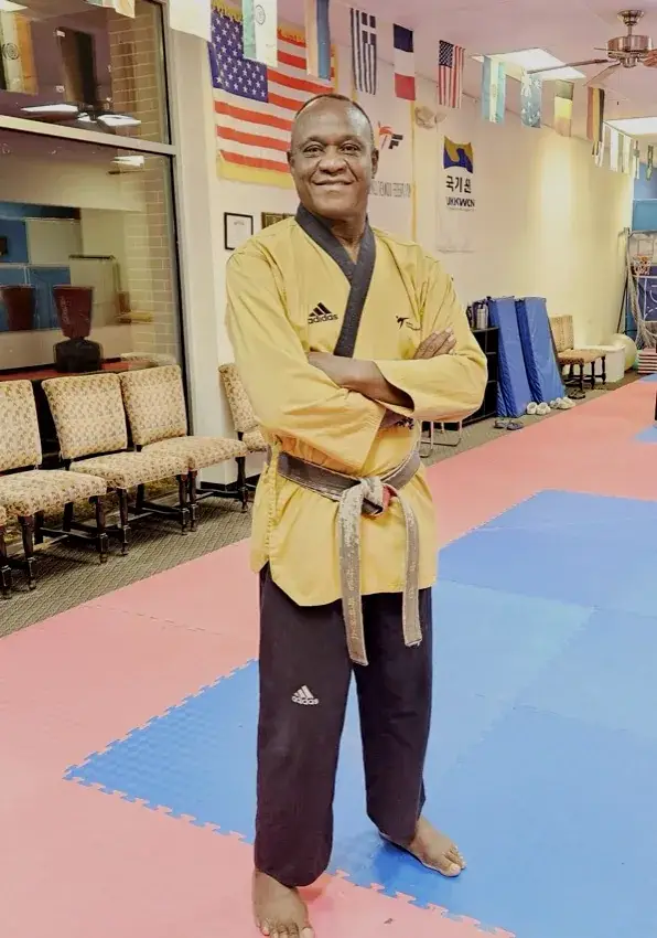 GrandMaster Pius Ilukhor, 8th-dan Taekwondo and founder of Master Pius Martial Arts, standing on the dojang floor